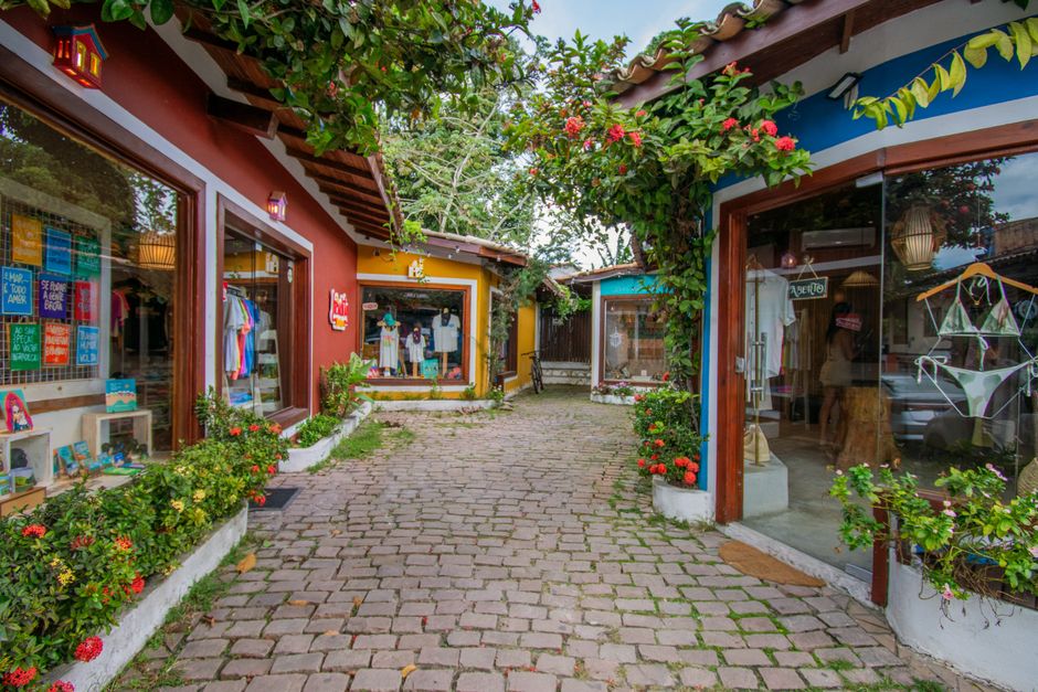 Rua de compras pitoresca em Arraial d'Ajuda, Bahia, Brasil, com vitrines coloridas.